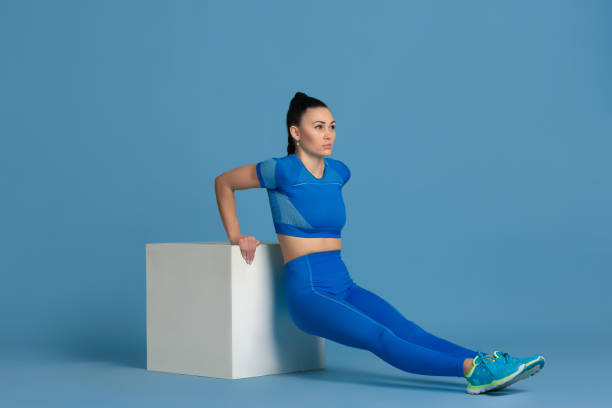 istock Beautiful young female athlete practicing on blue studio background, monochrome portrait 1218966875