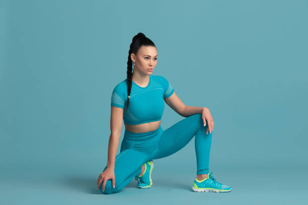 istock Beautiful young female athlete practicing on blue studio background, monochrome portrait 1218966888