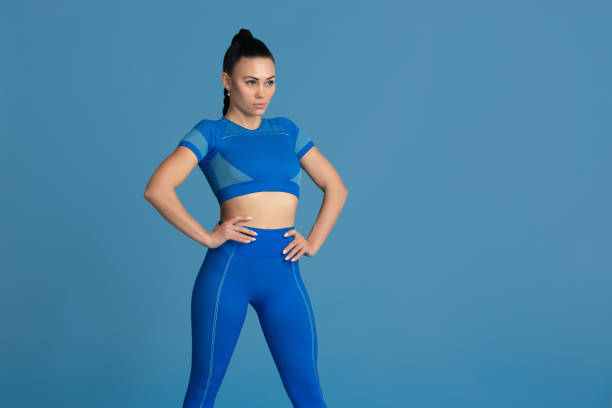 istock Beautiful young female athlete practicing on blue studio background, monochrome portrait 1218966898