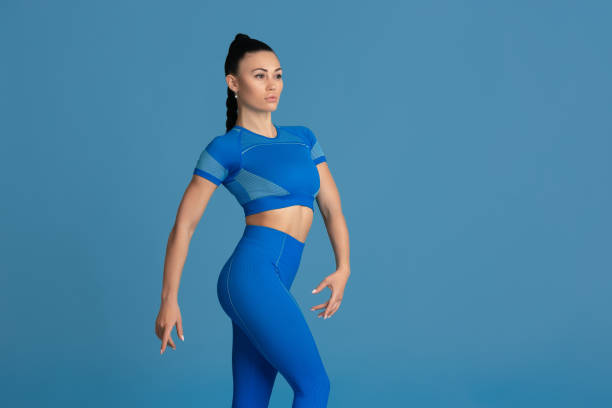 istock Beautiful young female athlete practicing on blue studio background, monochrome portrait 1218966904