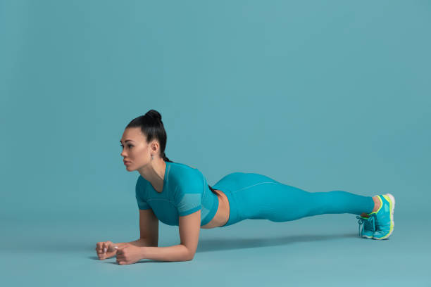 istock Beautiful young female athlete practicing on blue studio background, monochrome portrait 1218966914