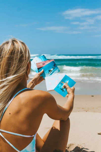 istock Girl on the beach looking at photos 1218967302