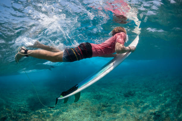 istock Underwater view of the surfer passing the wave with the surf board 1218967408