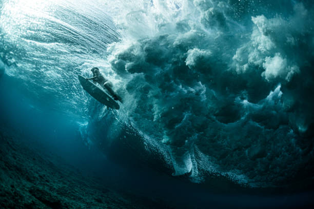 vue sous-marine de la femme surfeur passant la vague puissante d’océan - vague déferlante photos photos et images de collection
