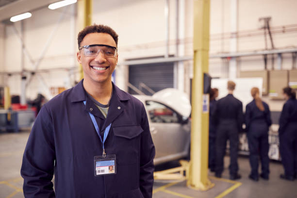 portrait of male student with safety glasses studying for auto mechanic apprenticeship at college - óculos de proteção imagens e fotografias de stock