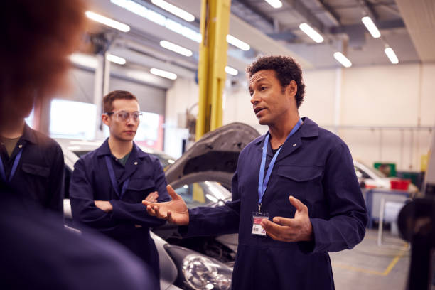istock Male Tutor With Students Teaching Auto Mechanic Apprenticeship At College 1218969940