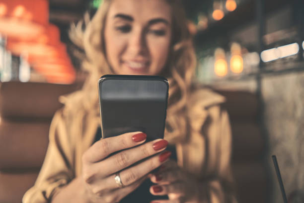 istock Young charming woman calling with cell telephone while sitting alone in coffee shop during free time, attractive female with cute smile having talking conversation with mobile phone while rest in cafe. 1218970003