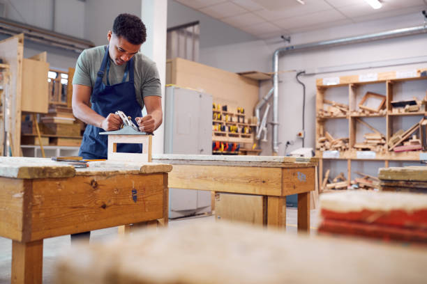 istock Male Student Studying For Carpentry Apprenticeship At College Using Wood Plane 1218970031