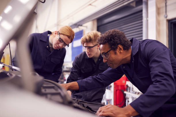 istock Male Tutor With Students Looking At Car Engine On Auto Mechanic Apprenticeship Course At College 1218970086