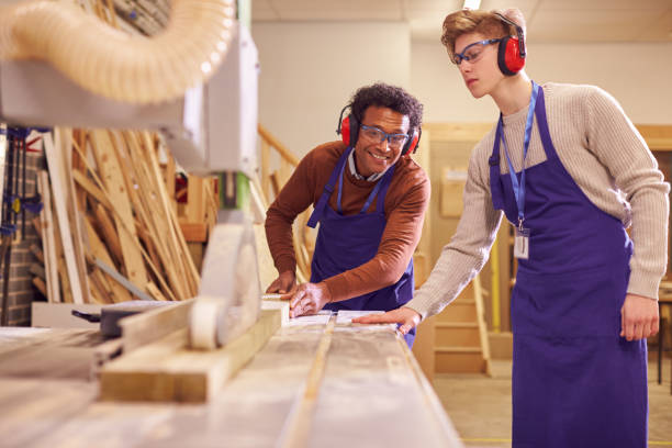 istock Tutor With Male Carpentry Student In Workshop Studying For Apprenticeship At College Using Bench Saw 1218970267