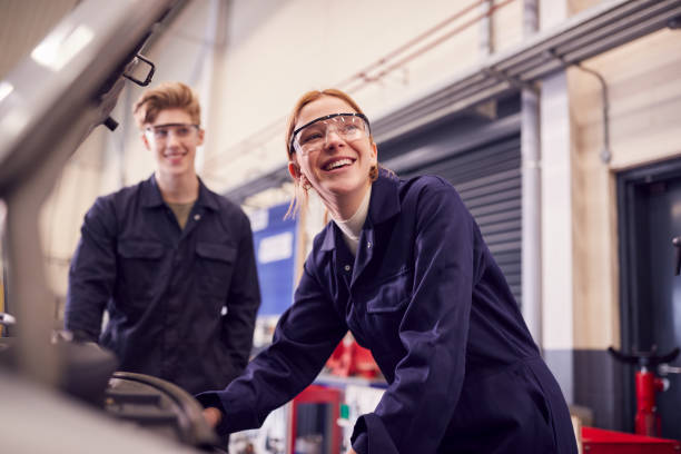 estudantes do sexo masculino e feminino olhando para motor de carro em curso de aprendizagem de mecânica de automóveis na faculdade - trainee - fotografias e filmes do acervo