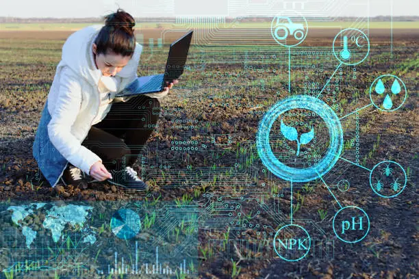 Photo of a farmer using a laptop and modern technology analyzes the data on humidity, temperature, light acidity, fertilizers and pests to increase yield
