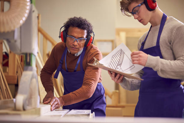 istock Tutor With Male Carpentry Student In Workshop Studying For Apprenticeship At College Using Bench Saw 1218971804
