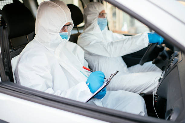 istock Man in protective suit in car stock photo 1218971830
