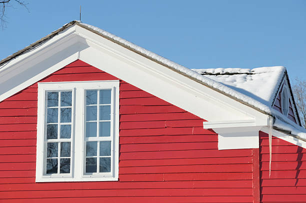 Peak of a rustic red building against a stormy sky.