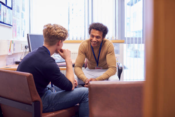 mannelijke college student vergadering met campus counselor bespreken geestelijke gezondheidsproblemen - beschermen stockfoto's en -beelden