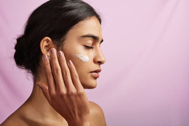 Nothing feels better than moisturized skin Studio shot of a beautiful young woman applying moisturizer to her face face cream stock pictures, royalty-free photos & images