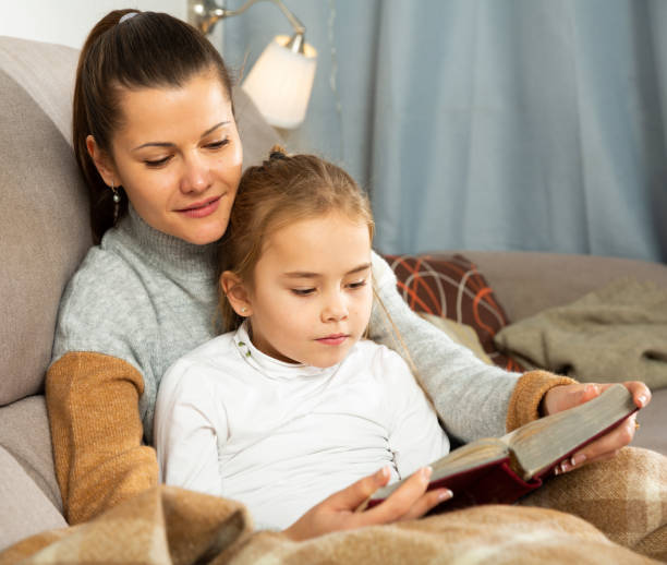 istock Young woman reading an interesting book with daughter 1218976144