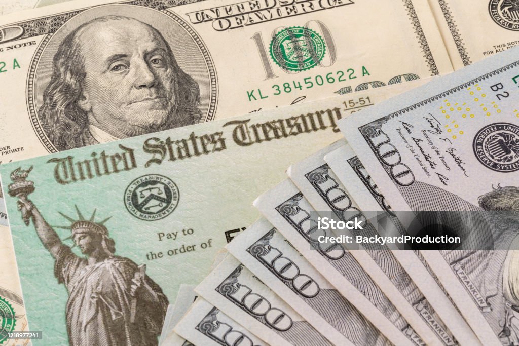 Illustration of the federal stimulus payment check with stack of cash surrounding payment Stack of 100 dollar bills with illustrative coronavirus stimulus payment check to show the virus stimulus payment to Americans Treasury Stock Photo
