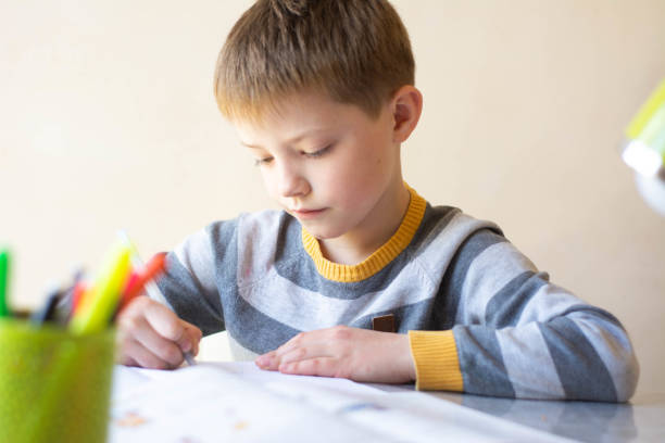 istock The boy does his homework. The child is learning remotely. A boy sits at a table and writes. Online learning 1218979836