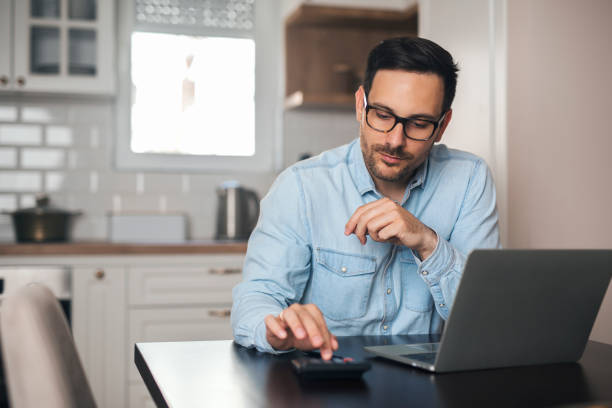 istock Young accountant count on calculator at home. 1218980017