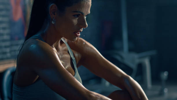 Beautiful Strong Fit Brunette in Sport Top and Shorts in a Loft Industrial Gym with Motivational Posters. She's Catching Her Breath after Intense Fitness Training Workout. Sweat All Over Her Face. Beautiful Strong Fit Brunette in Sport Top and Shorts in a Loft Industrial Gym with Motivational Posters. She's Catching Her Breath after Intense Fitness Training Workout. Sweat All Over Her Face. sweat stock pictures, royalty-free photos & images