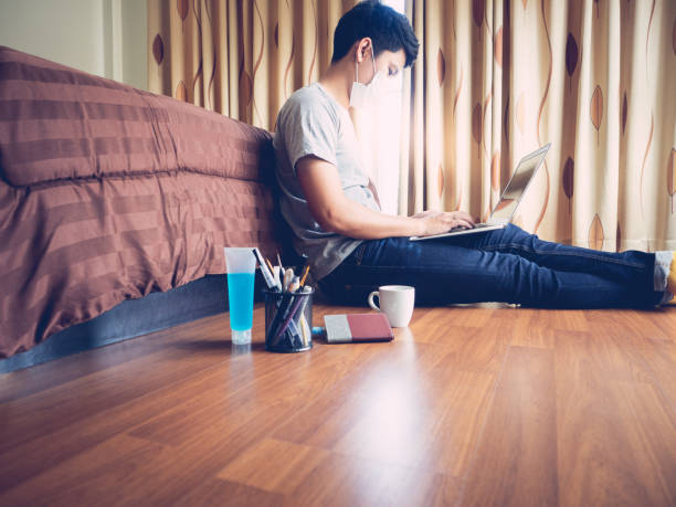 istock Work from home (WFH) concept. Man working on laptop computer sitting on the floor in bedroom. 1218981759