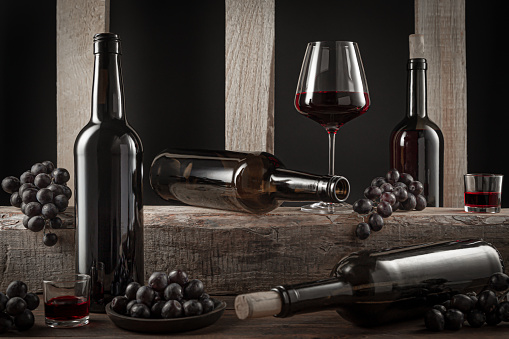 Bottles and glasses  of Spanish red wine and grapes on  wooden base on black background.