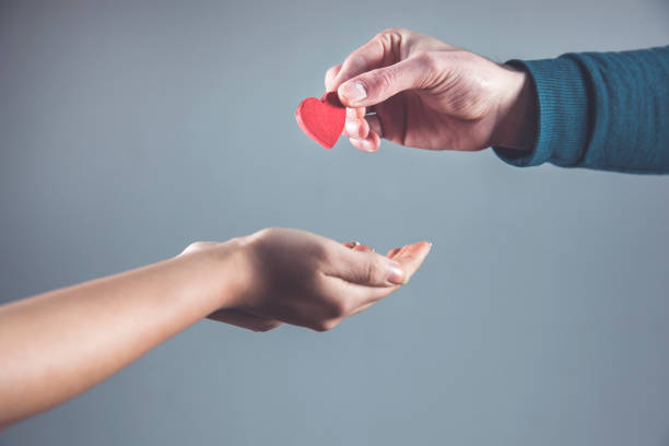woman and man hand red heart on gray wall abckground