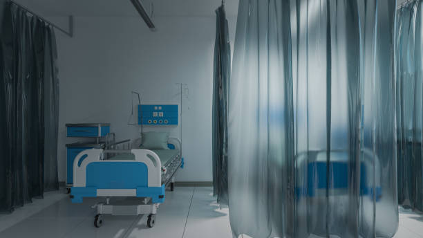 istock Empty Medical Beds Inside a Partially Illuminated Medical Room Separated with Curtains 1218985229