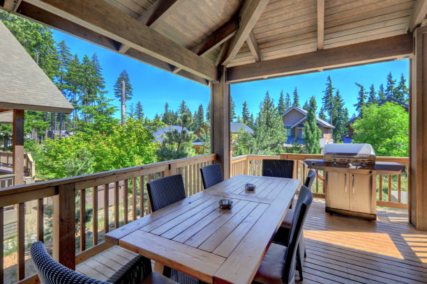 istock Beautiful covered deck with large luxury dining room table with grill and railings. 1218987606
