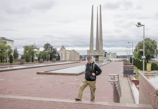 Vitebsk, Belarus - July 1, 2018: Asian tourist with a backpack walks along Victory Square on a cloudy day.
