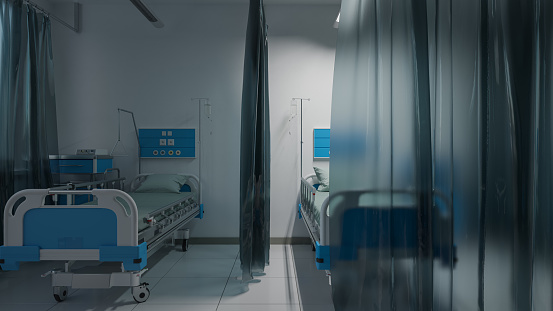 Camas de pacientes vacías dentro de un hospital parcialmente iluminado photo