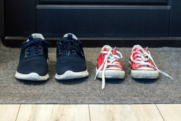 Family blue shoes and red sneakers on the rug at the front door. Closeup view Family blue shoes and red sneakers on the rug at the front door. Closeup view running shoes on floor stock pictures, royalty-free photos & images