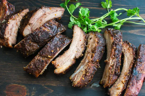 Spicy barbecued baby back ribs on a wood cutting board