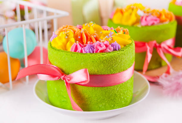 istock Spring Easter festive table. Small green cakes with butter cream flowers and colorful eggs on the background. 1218994473