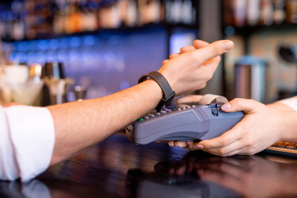 istock Young client with smartwatch keeping his wrist over payment machine 1218997138
