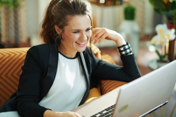istock smiling stylish woman typing message while sitting on sofa 1218998463