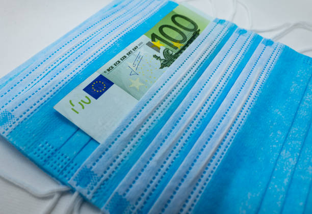 100 Euro bank note with protective surgical face masks stock photo