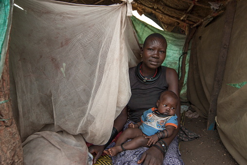 Juba, South Sudan - February 28th, 2012: Unidentified woman with baby sits in makeshift hovel in displaced persons camp, Juba, South Sudan. Refugees stay in harsh conditions in camps of Juba.