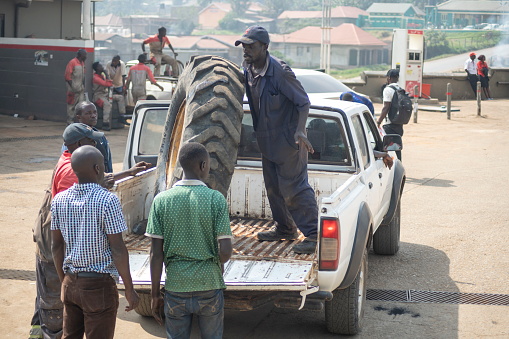 Fort Portal, Uganda - January 25th, 2020: Unidentified workers unload a wheel from a pickup car in Fort Portal, Uganda. Uganda is a fast developing African country with all conditions for small business.