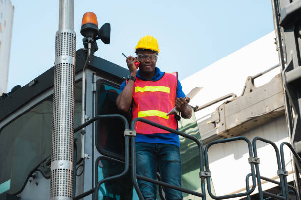 istock Black foreman worker working control the crane and forklift at Container cargo harbor to loading containers. African dock male staff with radio walkie-talkie for Logistics import export shipping concept. 1219004834