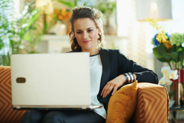 istock happy female checking website on laptop while sitting on couch 1219007223