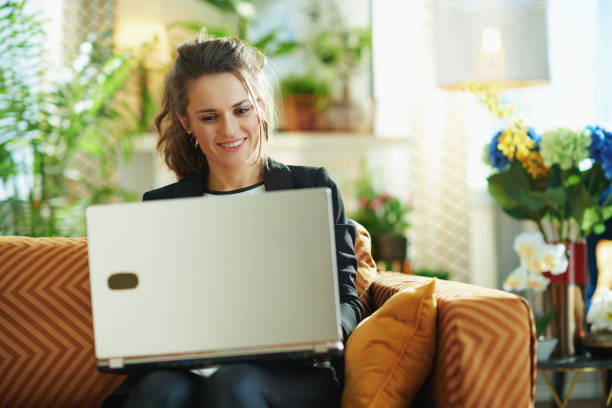 istock smiling elegant middle age woman with laptop sitting on couch 1219007224