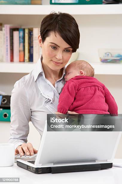 Woman With Newborn Baby Working From Home Using Laptop Stock Photo - Download Image Now