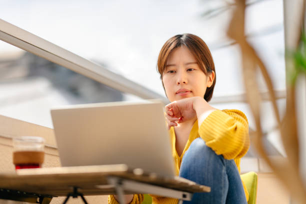 junge frau mit laptop bequem auf balkon zu hause - comfortably stock-fotos und bilder