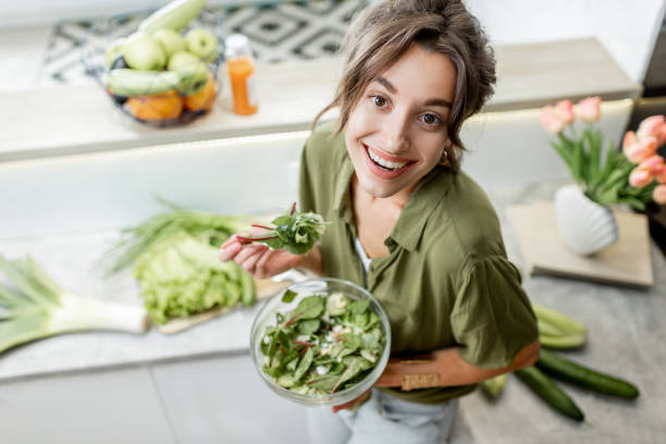 istock Woman eating salad on the kitchen at home 1219009698