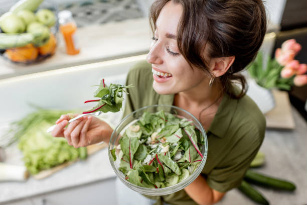 istock Woman eating salad on the kitchen at home 1219009707