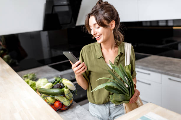 自宅の台所で新鮮な食料品を持つ女性 - supermarket groceries shopping healthy lifestyle ストックフォトと画像