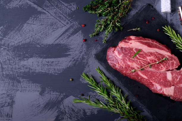 istock Raw marbled beef steak, herbs and spices against the grey background 1219010104